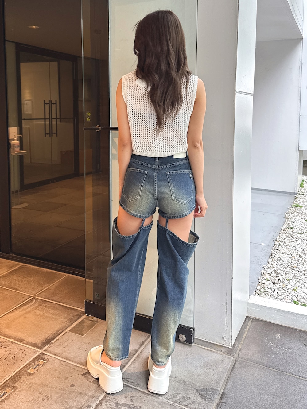 ホワイト系のタンクトップ、ブルー系のデニムパンツ、ホワイト系のサンダルを着用したレディースの春コーディネートの4枚目の写真