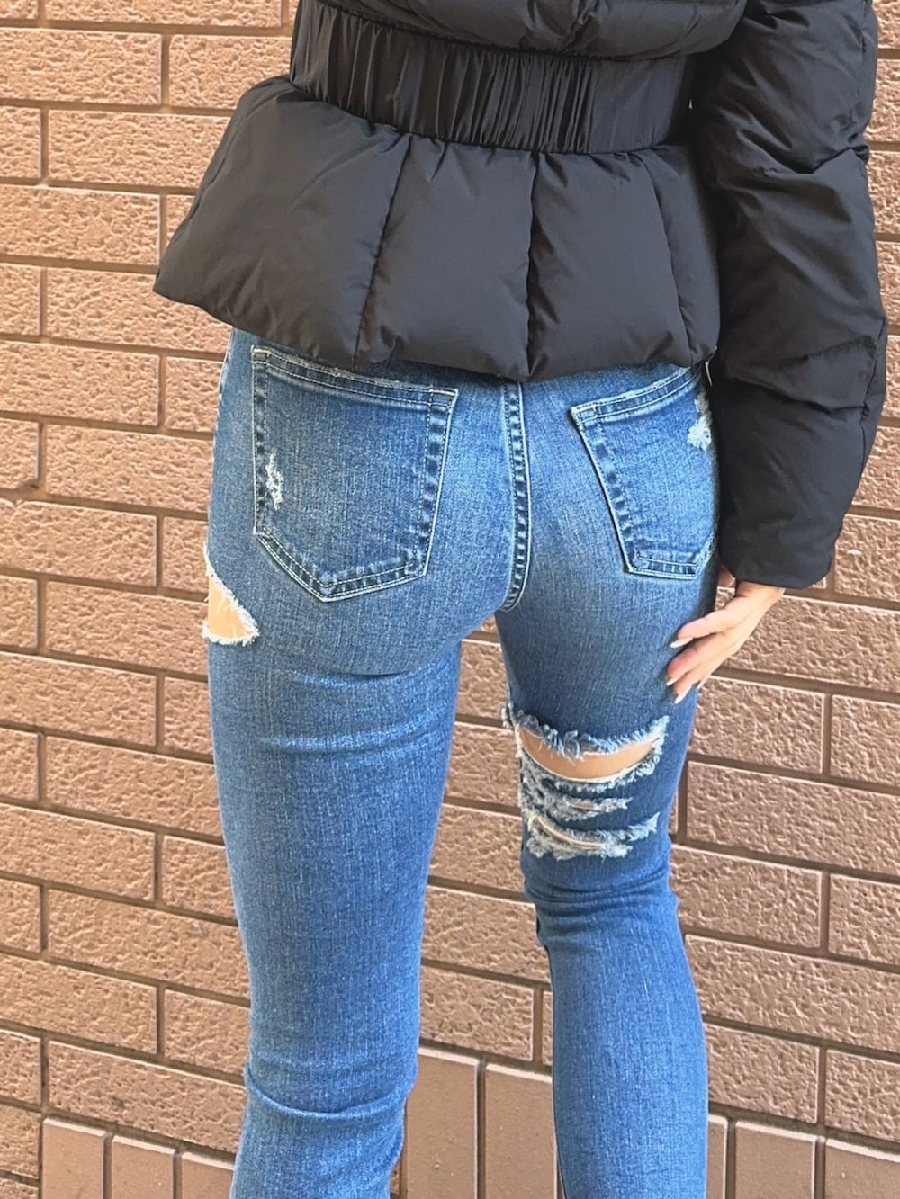 ブラック系のダウンジャケット/コート、ブラック系のニット/セーター、ブルー系のデニムパンツを着用したレディースの秋コーディネートの9枚目の写真