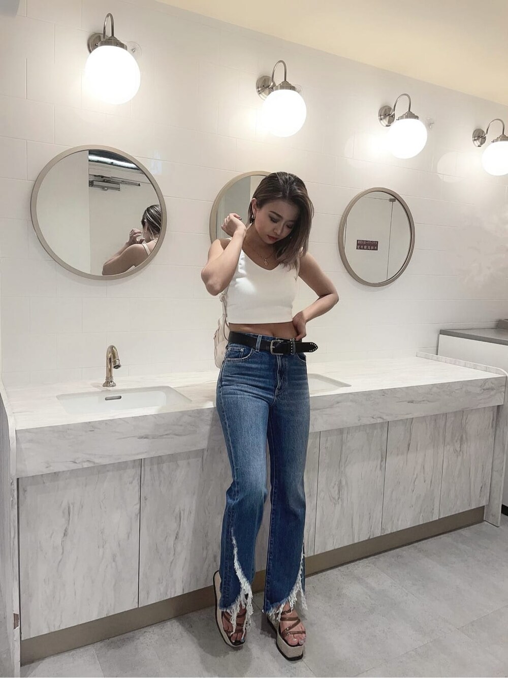 ブルー系のデニムパンツ、ホワイト系のキャミソール、ブラック系のサンダルを着用したレディースの夏コーディネートの2枚目の写真