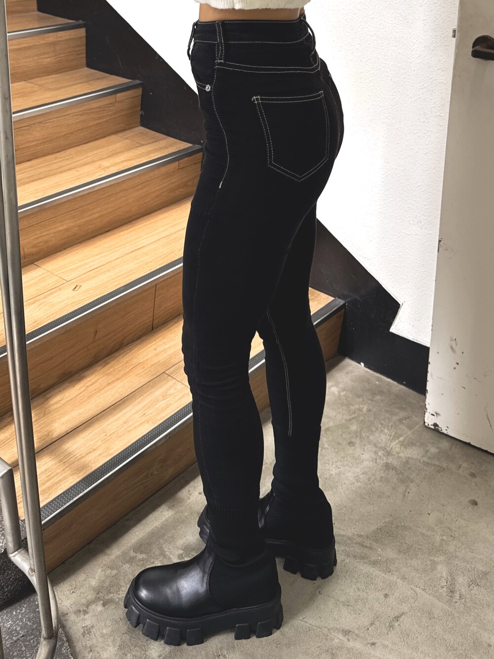 ブルー系のニット/セーター、ブラック系のデニムパンツ、ブラック系のブーツを着用したレディースの秋コーディネートの5枚目の写真