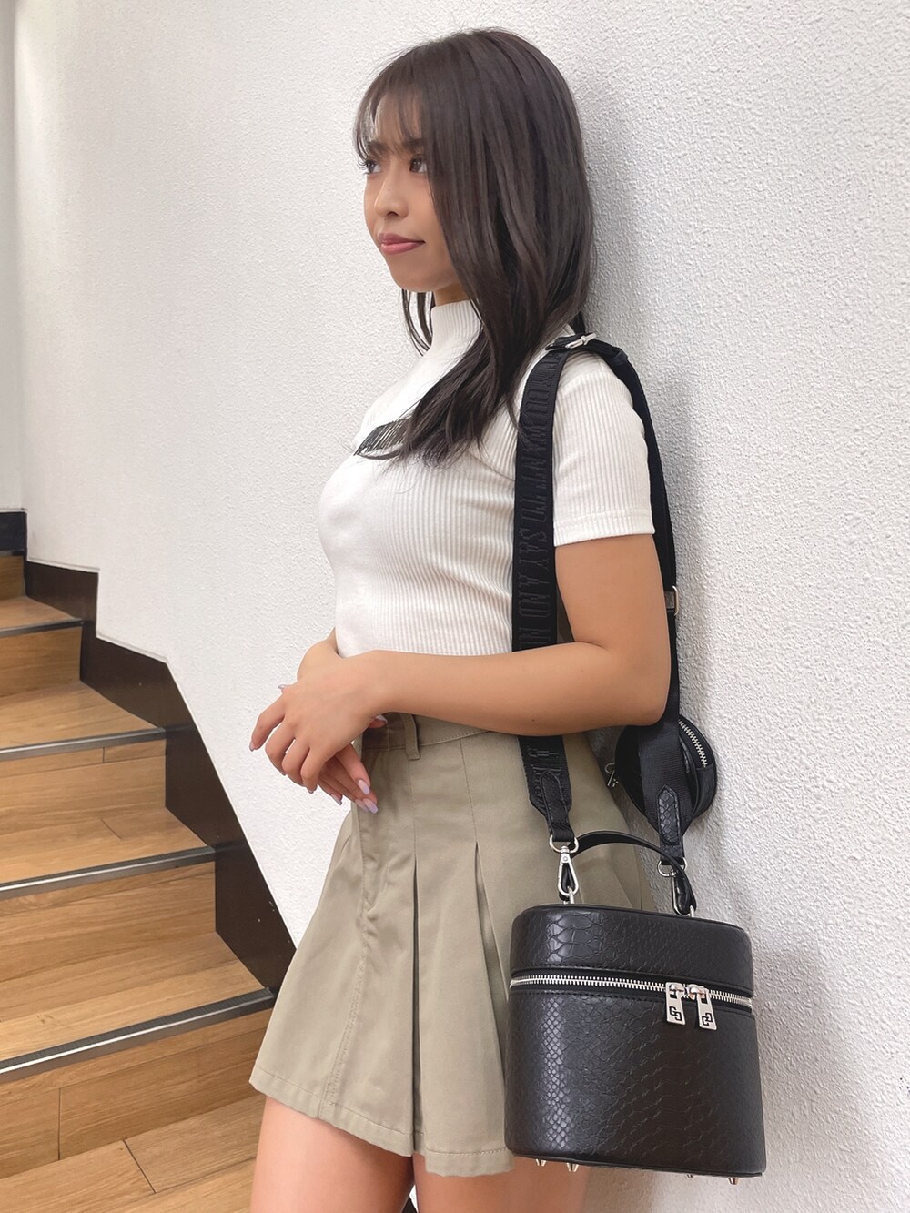 ブラック系のブーツ、ブラック系のハンドバッグ、ベージュ系のスカートを着用したレディースの春コーディネートの4枚目の写真