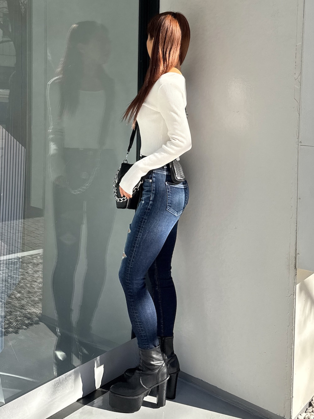 ホワイト系のニット/セーター、ブルー系のデニムパンツ、ブラック系のブーツを着用したレディースの冬コーディネートの2枚目の写真