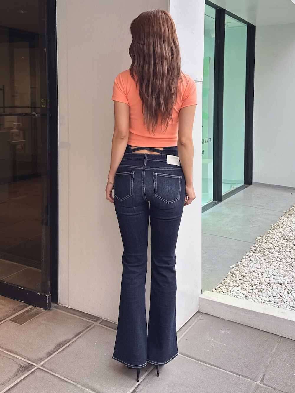 オレンジ系のTシャツ/カットソー、ブルー系のデニムパンツ、ブラック系のパンプスを着用したレディースの春コーディネートの4枚目の写真