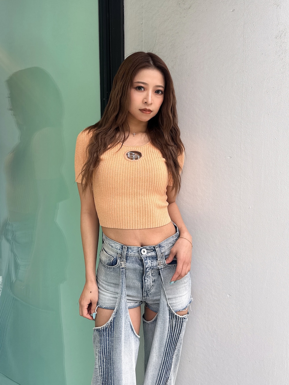 オレンジ系のニット/セーター、ブルー系のデニムパンツ、ホワイト系のパンプスを着用したレディースの春コーディネートの5枚目の写真