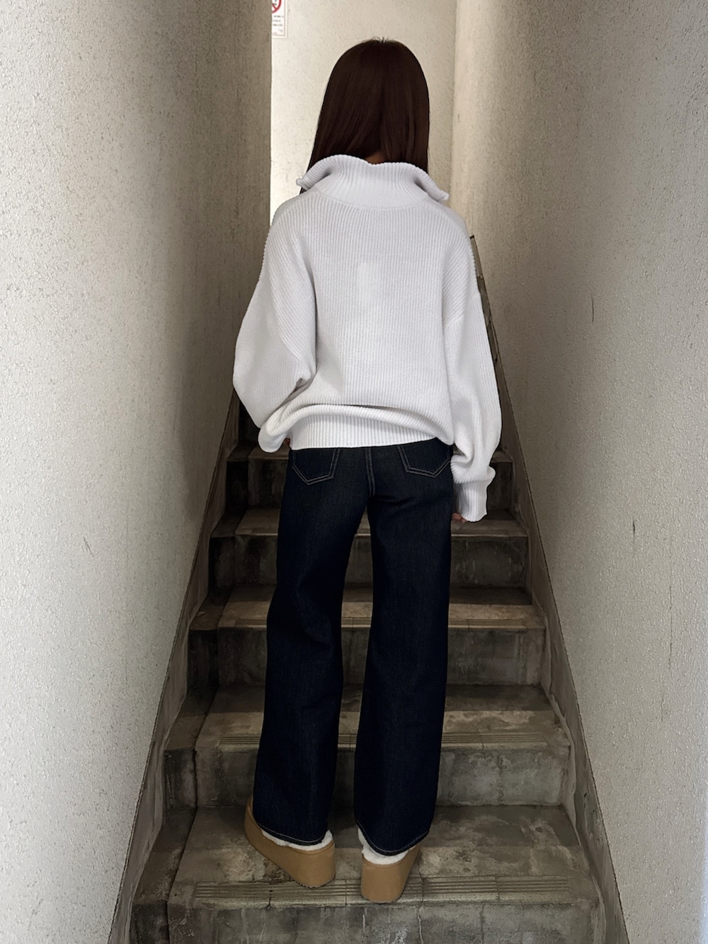 ホワイト系のニット/セーター、ブルー系のデニムパンツ、ベージュ系のスリッポンを着用したレディースの冬コーディネートの3枚目の写真