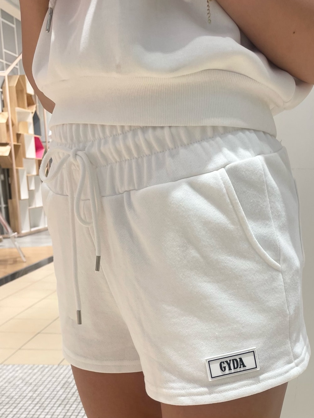 ホワイト系のパーカー、ホワイト系のスウェットパンツ、ブラック系のスニーカーを着用したレディースの夏コーディネートの7枚目の写真