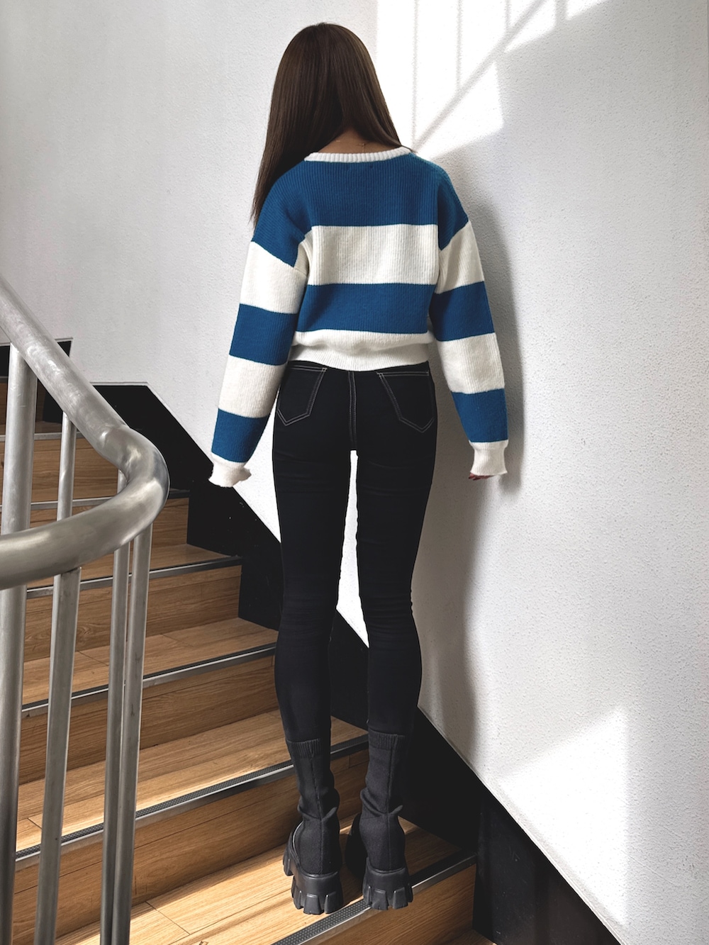 ブルー系のニット/セーター、ブラック系のデニムパンツ、ブラック系のブーツを着用したレディースの秋コーディネートの3枚目の写真
