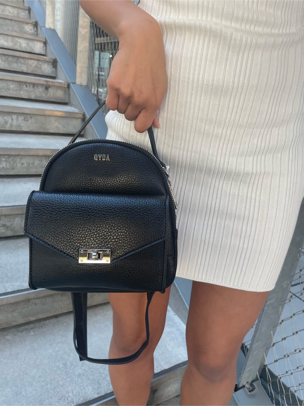 ブラック系のパンプス、ホワイト系のワンピース、ブラック系のバックパック/リュックを着用したレディースの春コーディネートの7枚目の写真