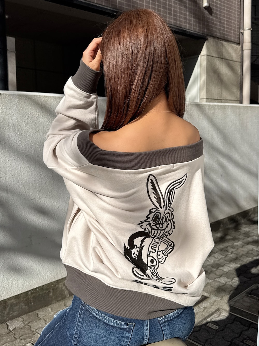 ホワイト系のスウェット、ブラック系のショルダーバッグ、ブルー系のデニムパンツを着用したレディースの冬コーディネートの4枚目の写真