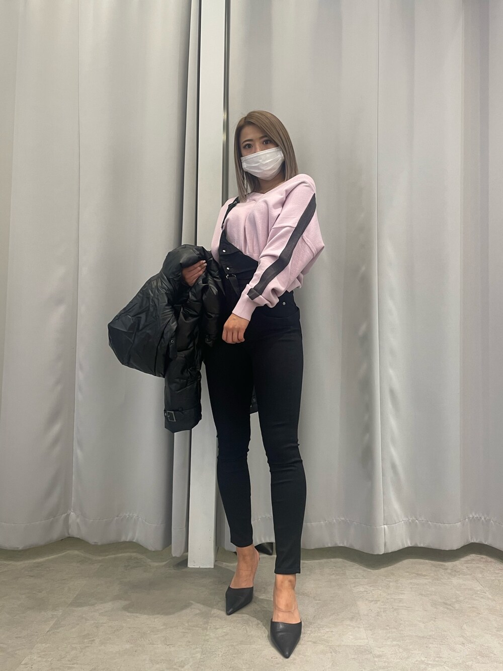 ブラック系のサロペット/オーバーオール、ピンク系のニット/セーター、ブラック系のダウンジャケット/コートを着用したレディースの冬コーディネートの2枚目の写真