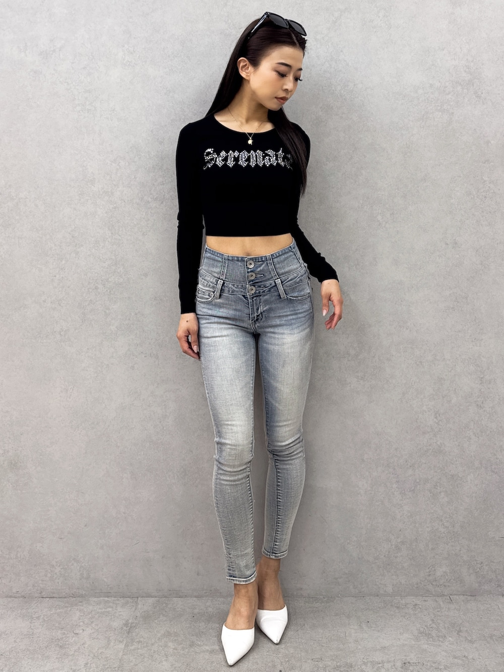 ブラック系のニット/セーター、ブルー系のデニムパンツ、ホワイト系のパンプスを着用したレディースの春コーディネートの2枚目の写真