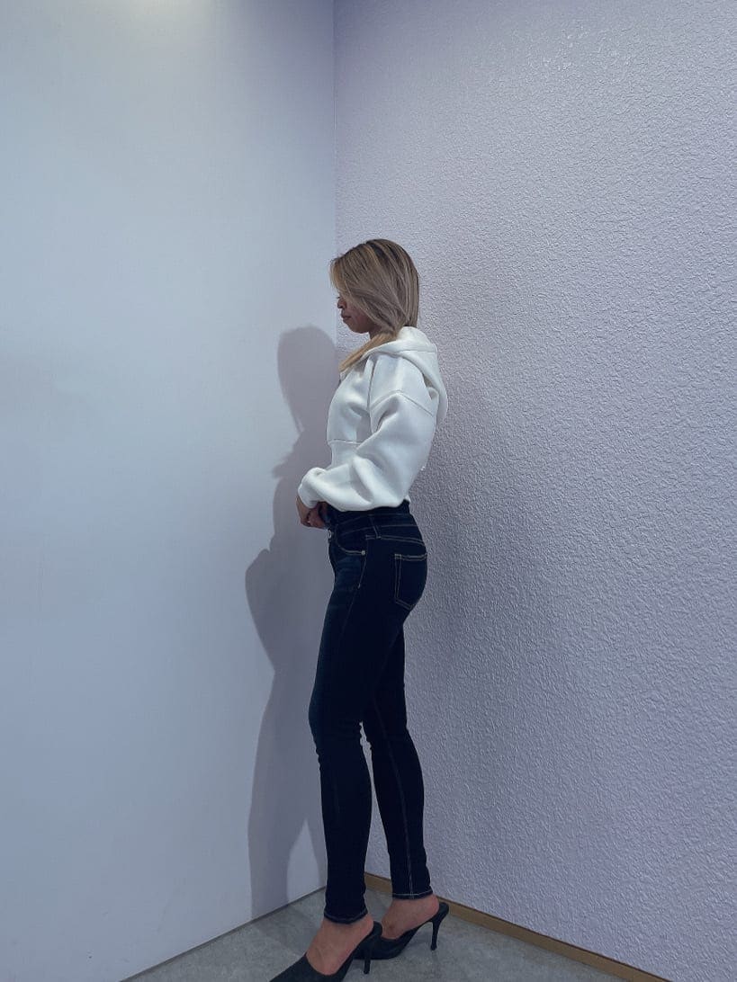 ブルー系のデニムパンツ、ホワイト系のパーカー、ブラック系のパンプスを着用したレディースの秋コーディネートの2枚目の写真