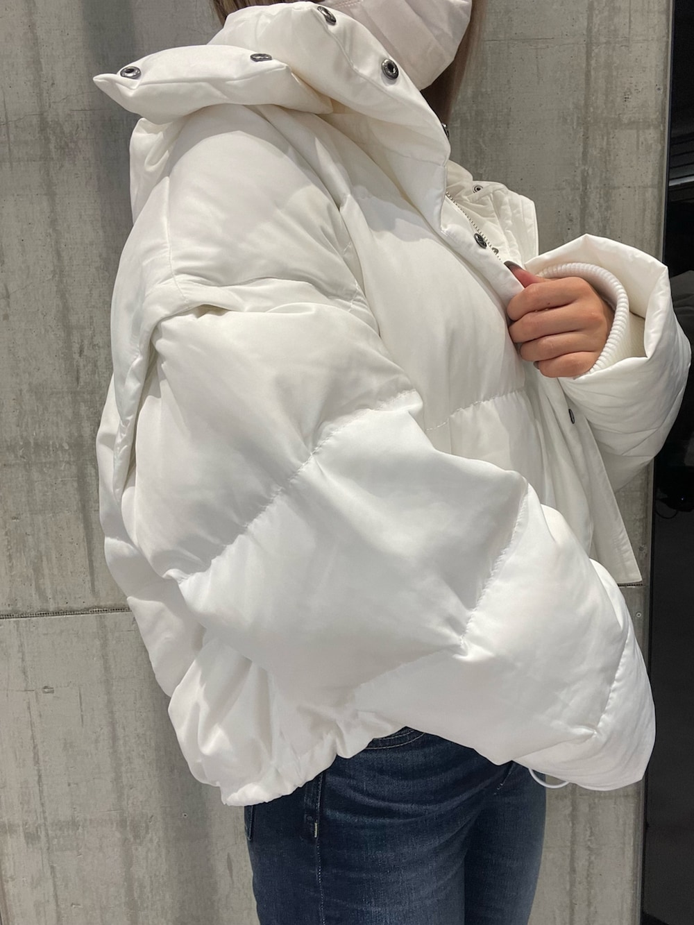 ブルー系のパンツ、ホワイト系のダウンジャケット/コート、ホワイト系のニット/セーターを着用したレディースの冬コーディネートの6枚目の写真