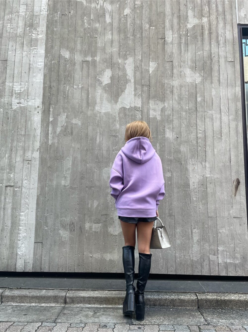 パープル系のTシャツ/カットソー、ブラック系のブーツ、ブラック系のスカートを着用したレディースの冬コーディネートの2枚目の写真