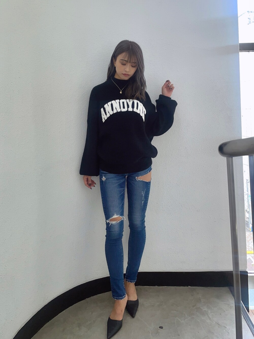 ブラック系のニット/セーター、ブルー系のデニムパンツ、ブラック系のパンプスを着用したレディースの秋コーディネートの2枚目の写真