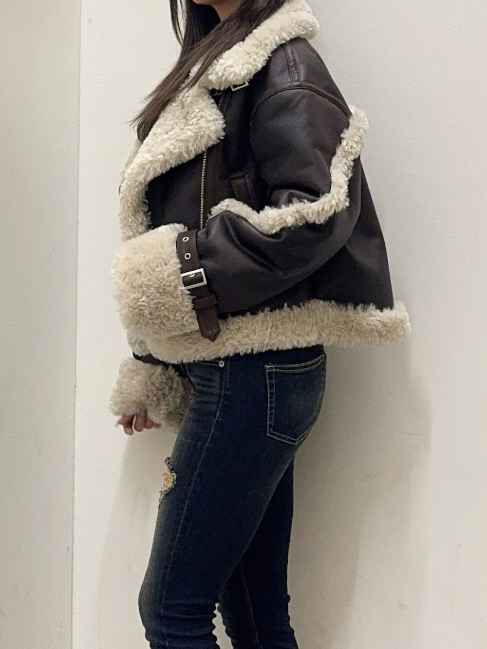 ホワイト系のTシャツ/カットソー、ブラウン系のムートンコート、ブルー系のデニムパンツを着用したレディースの秋コーディネートの5枚目の写真