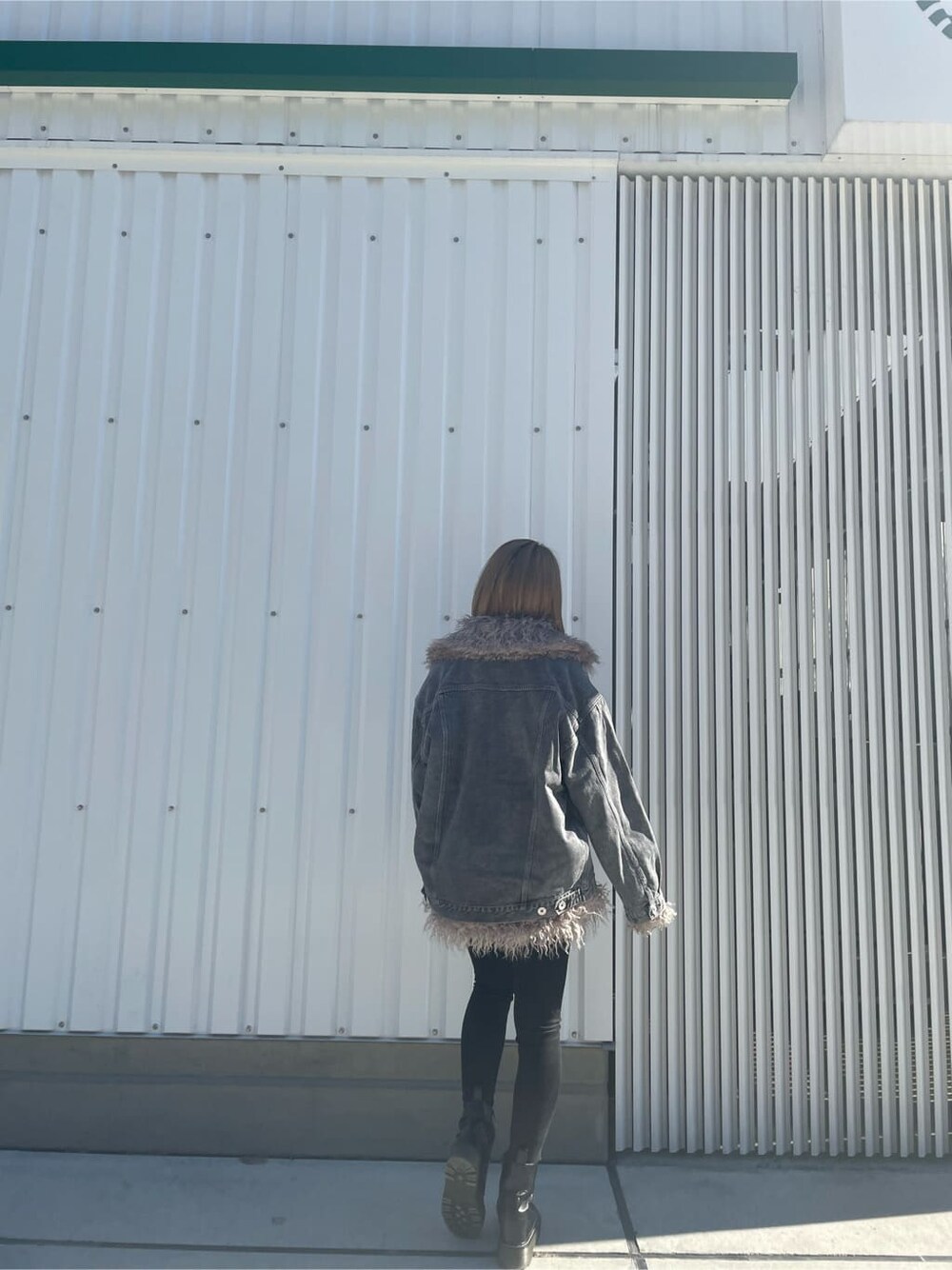 ブラック系のブーツ、ブラック系のデニムパンツ、ホワイト系のニット/セーターを着用したレディースの秋コーディネートの3枚目の写真