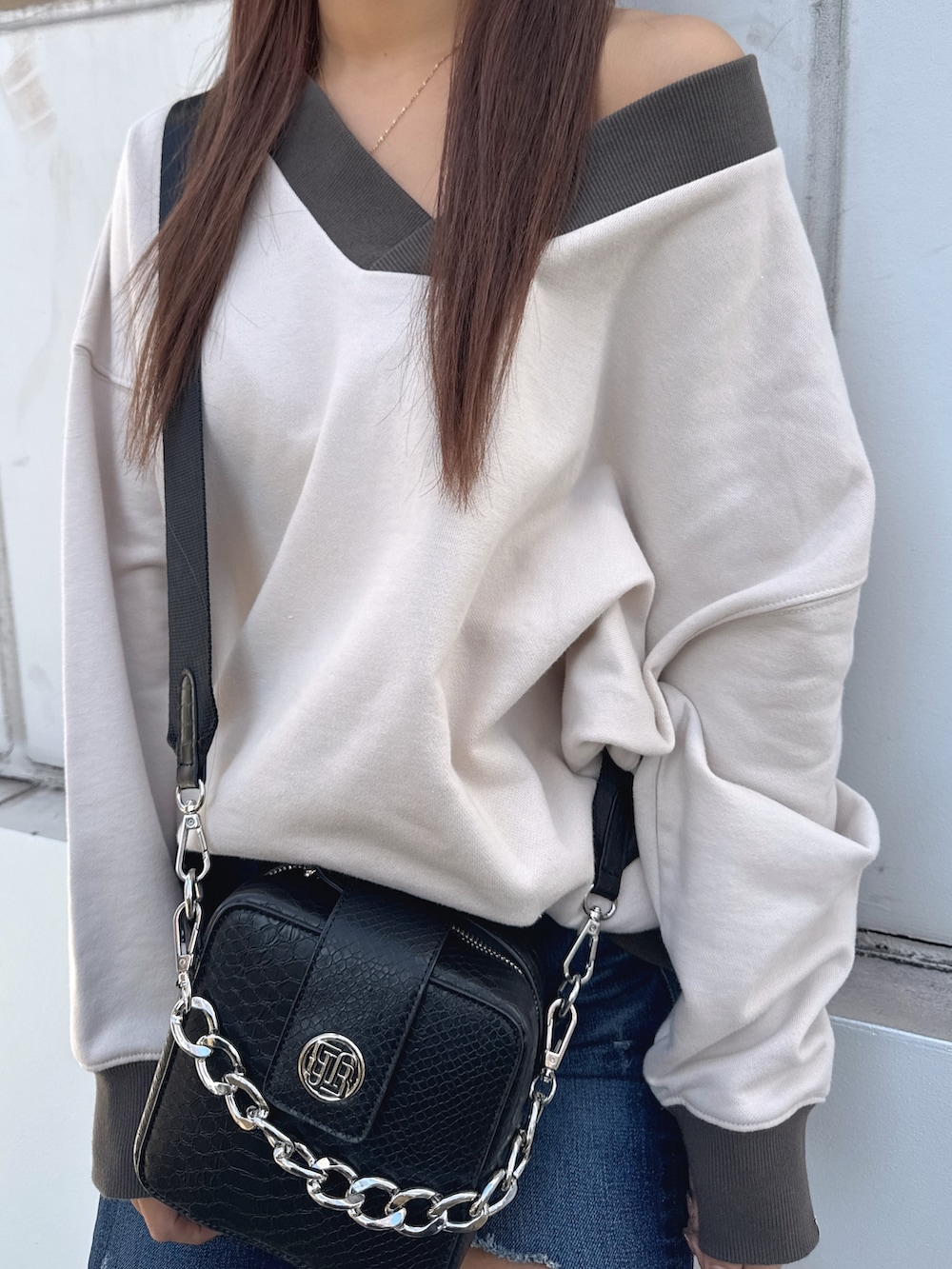 ホワイト系のスウェット、ブラック系のショルダーバッグ、ブルー系のデニムパンツを着用したレディースの冬コーディネートの3枚目の写真