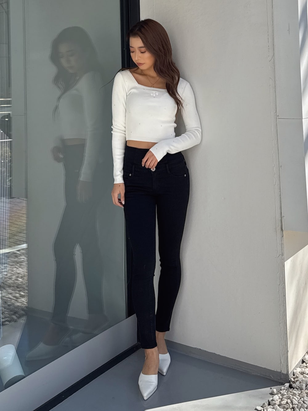 ホワイト系のニット/セーター、ブラック系のデニムパンツ、ホワイト系のパンプスを着用したレディースの春コーディネートの2枚目の写真