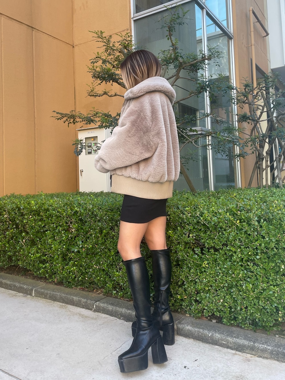 ベージュ系のブルゾン、ブラック系のワンピース、ブラック系のブーツを着用したレディースの冬コーディネートの3枚目の写真