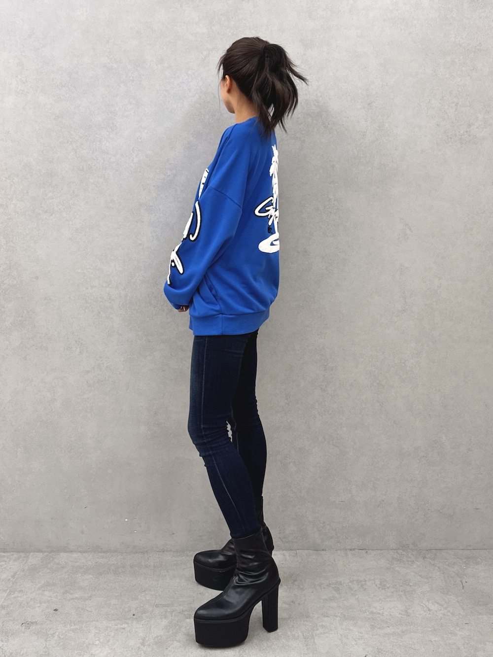 ブルー系のスウェット、ブルー系のデニムパンツ、ブラック系のブーツを着用したレディースの秋コーディネートの2枚目の写真