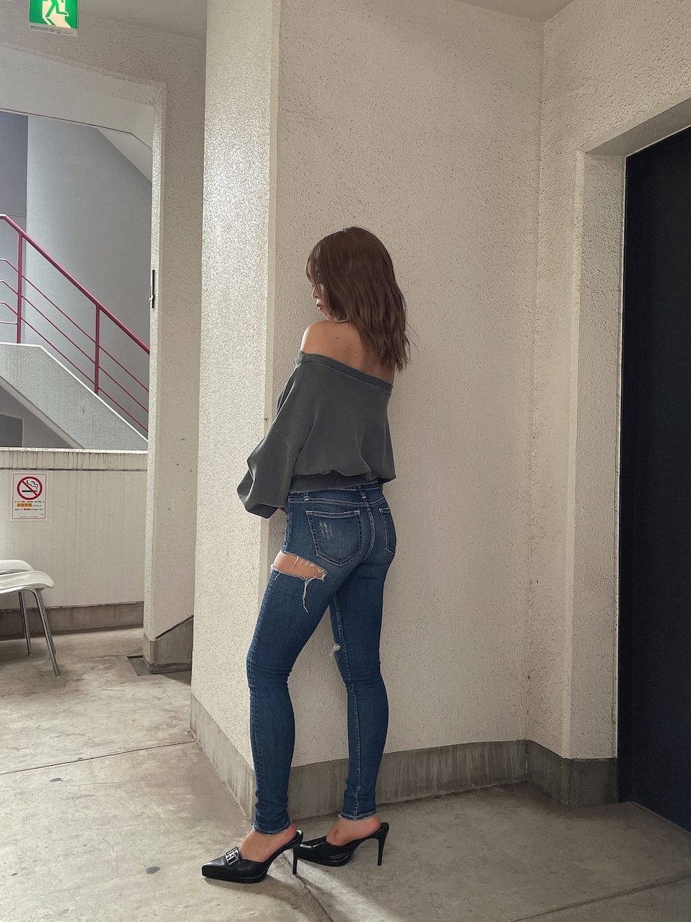 グレー系のスウェット、ブルー系のデニムパンツ、ブラック系のパンプスを着用したレディースの夏コーディネートの2枚目の写真