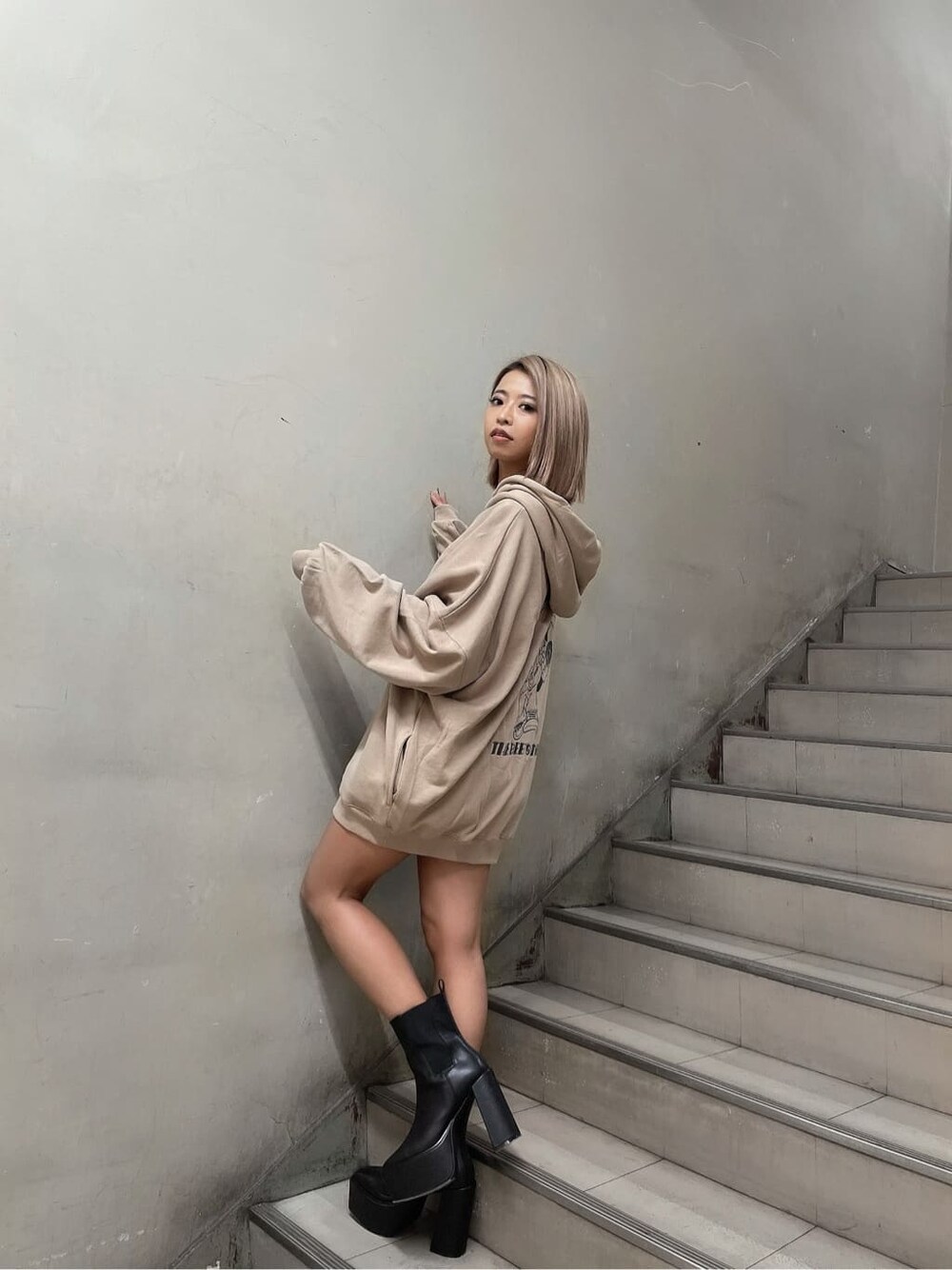 ブラック系のブーツ、ベージュ系のパーカー、ゴールド系のネックレスを着用したレディースの秋コーディネートの2枚目の写真