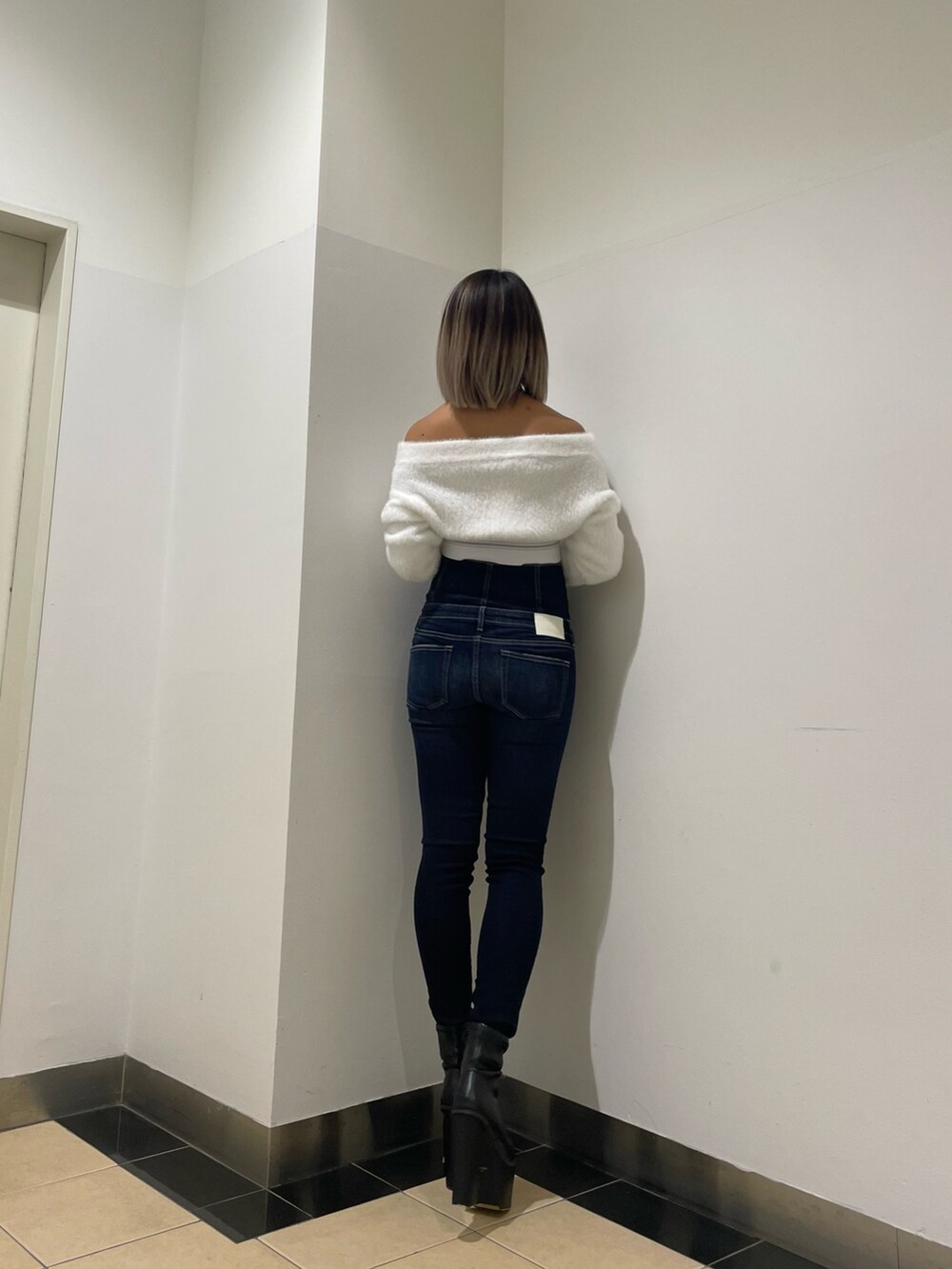 ブルー系のパンツ、ホワイト系のニット/セーター、ブラック系のブーツを着用したレディースの秋コーディネートの3枚目の写真