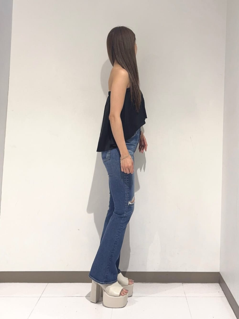 ホワイト系のサンダル、ブルー系のデニムパンツ、ブラック系のチューブトップを着用したレディースの夏コーディネートの2枚目の写真
