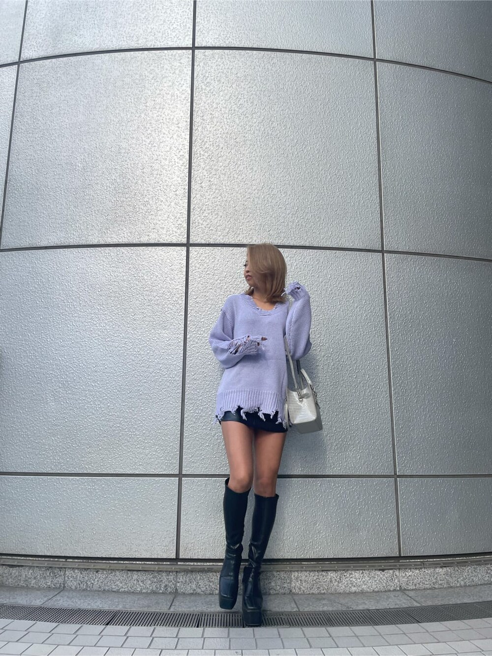 パープル系のニット/セーター、グレー系のハンドバッグ、ブラック系のブーツを着用したレディースの冬コーディネートの2枚目の写真