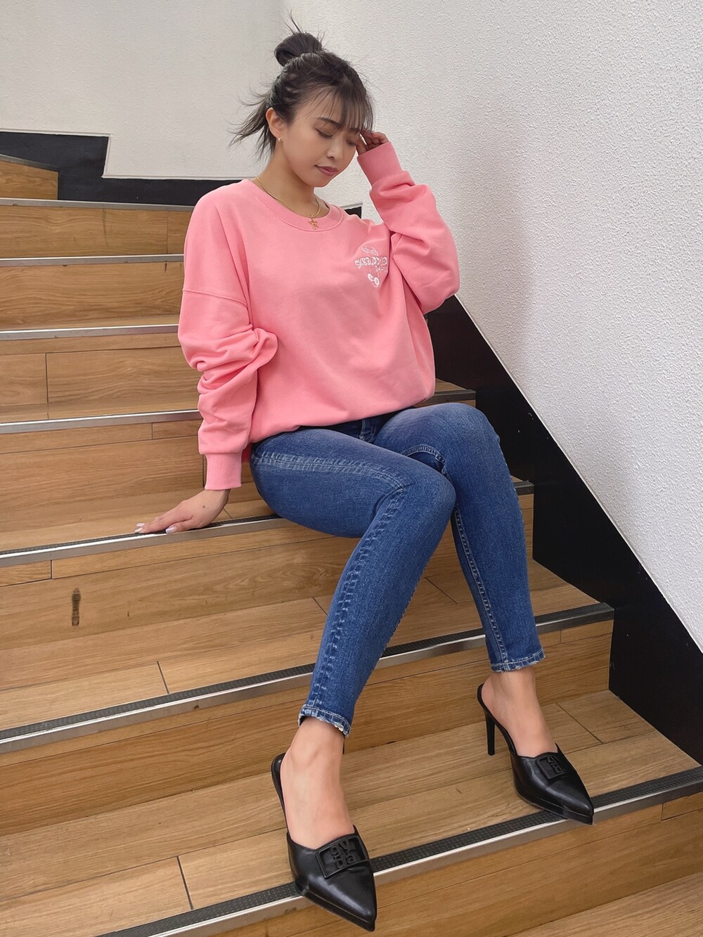 ピンク系のスウェット、ブルー系のデニムパンツ、ブラック系のパンプスを着用したレディースの春コーディネートの2枚目の写真