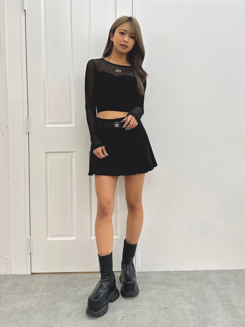 グレー系のスカート、ブラック系のニット/セーター、ブラック系のブーツを着用したレディースの夏コーディネートの2枚目の写真