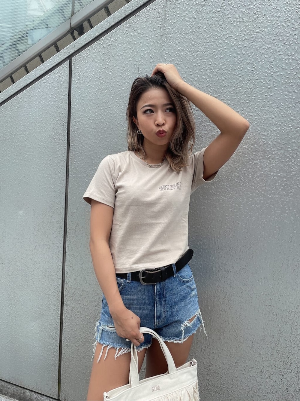 ブルー系のデニムパンツ、ホワイト系のハンドバッグ、ベージュ系のTシャツ/カットソーを着用したレディースの夏コーディネートの3枚目の写真