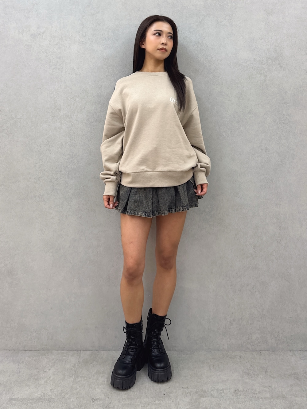 ベージュ系のスウェット、ブルー系のデニムスカート、ブラック系のブーツを着用したレディースの春コーディネートの2枚目の写真