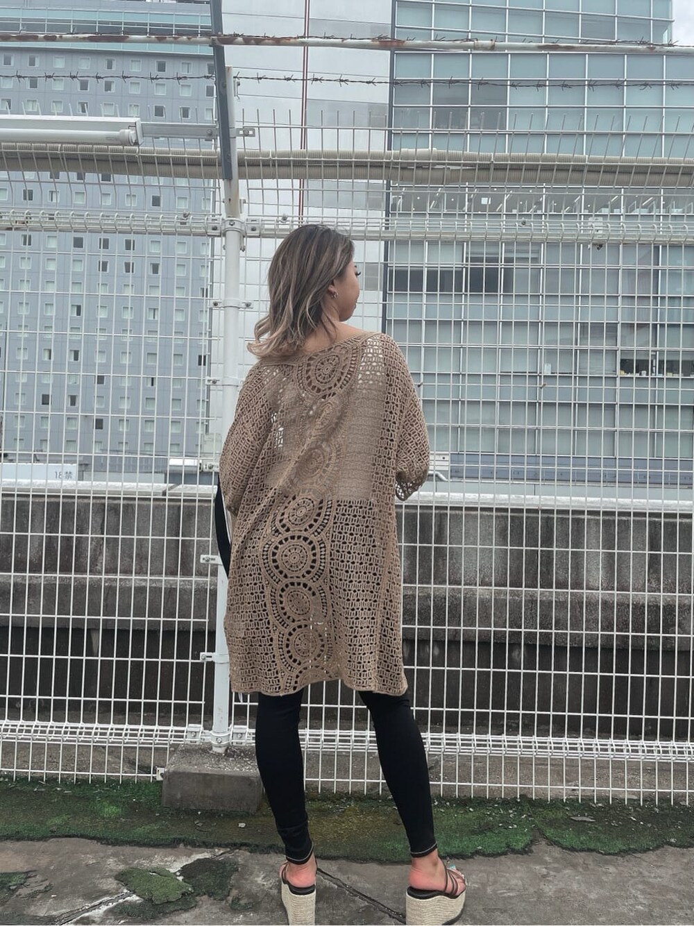 ホワイト系のニット/セーター、ブラック系のデニムパンツ、ブラック系のサンダルを着用したレディースの夏コーディネートの2枚目の写真