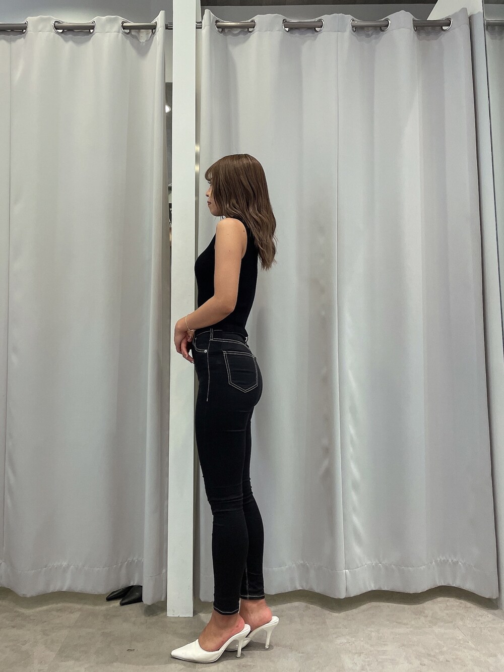 ブラック系のニット/セーター、ブラック系のデニムパンツ、ホワイト系のパンプスを着用したレディースの夏コーディネートの2枚目の写真