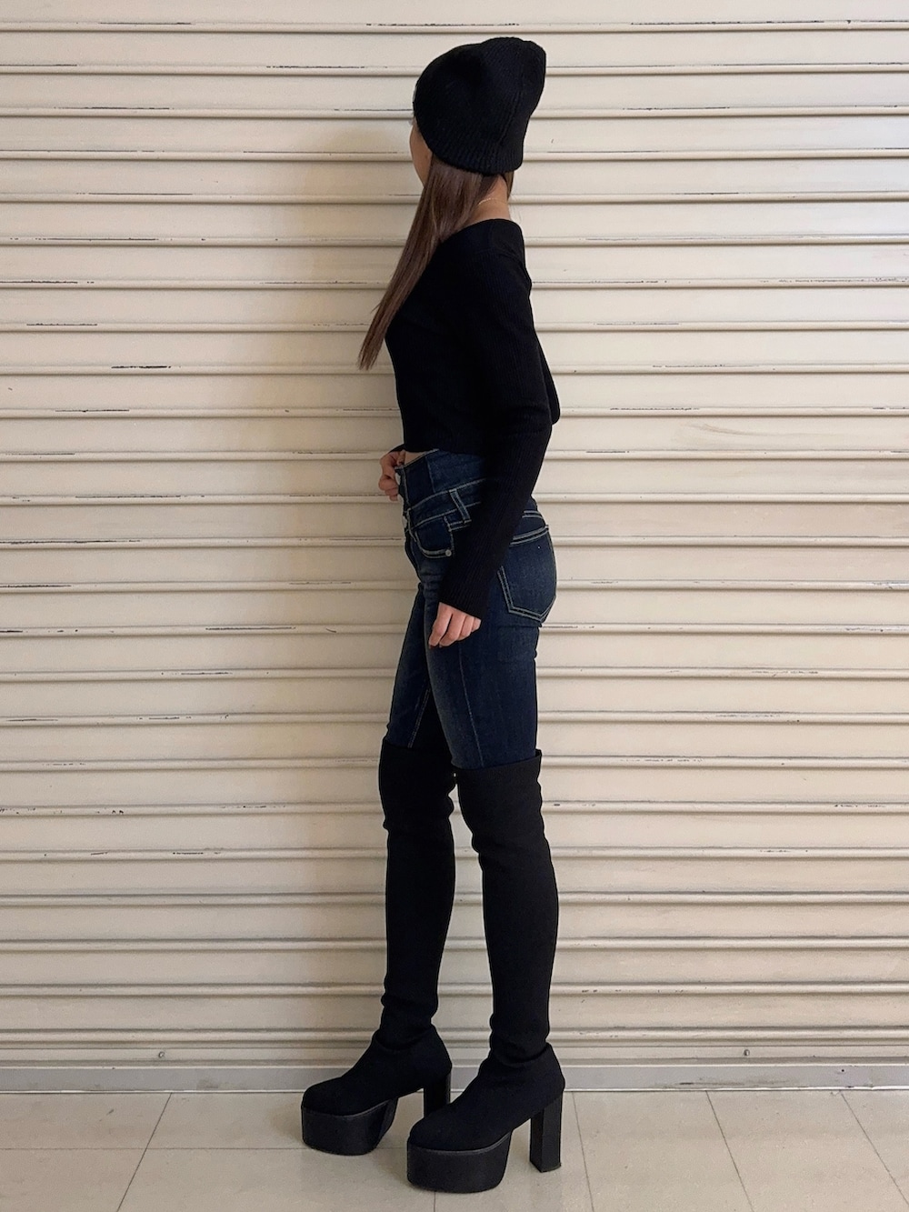 ブラック系のニット/セーター、ブルー系のデニムパンツ、ブラック系のブーツを着用したレディースの秋コーディネートの2枚目の写真