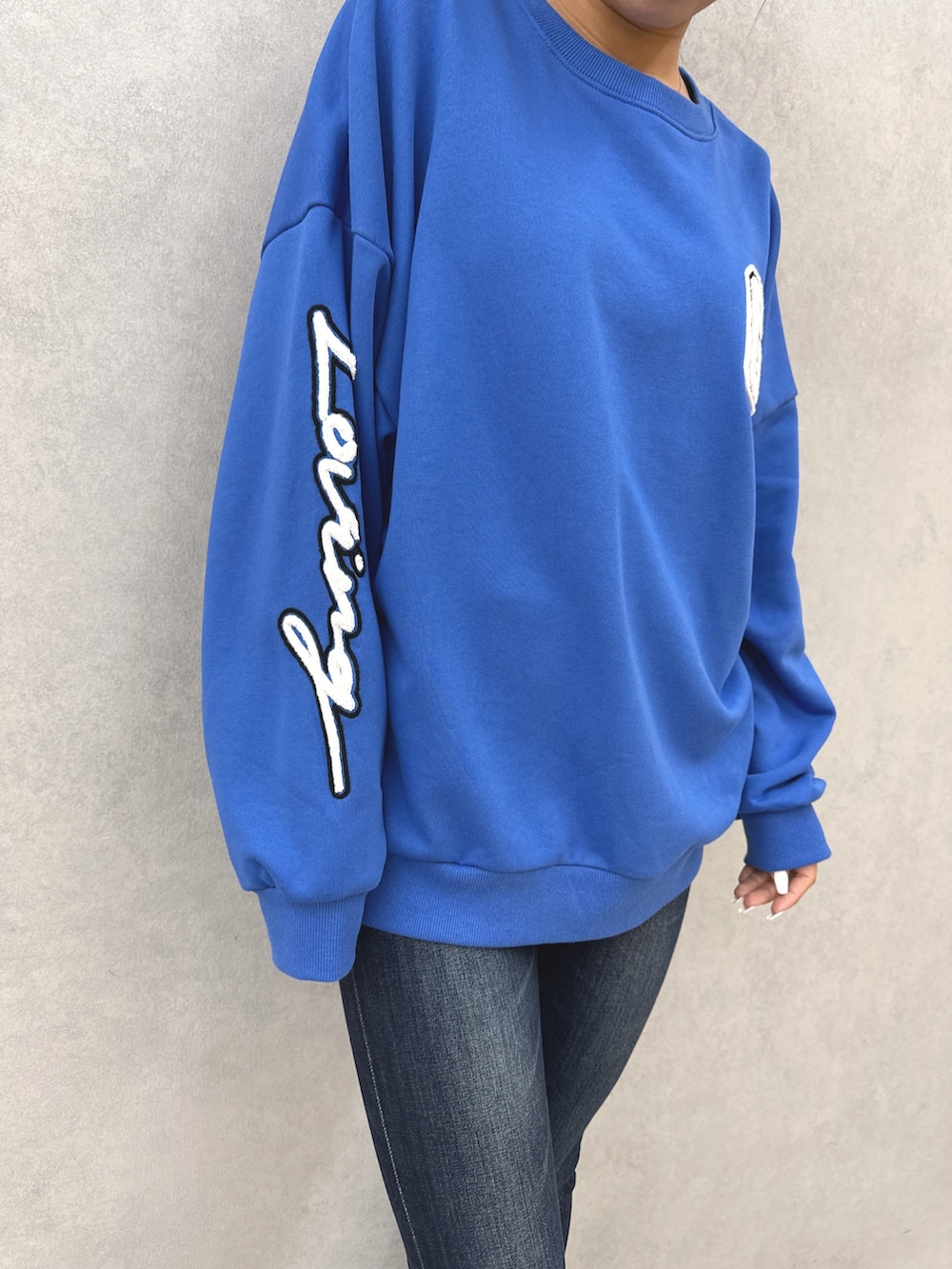 ブルー系のスウェット、ブルー系のデニムパンツ、ブラック系のブーツを着用したレディースの秋コーディネートの6枚目の写真