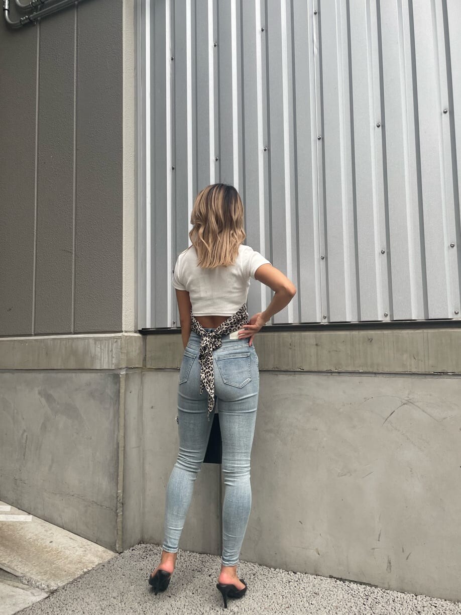 ホワイト系のパンプス、ブラック系のハンドバッグ、ブルー系のデニムパンツを着用したレディースの夏コーディネートの3枚目の写真