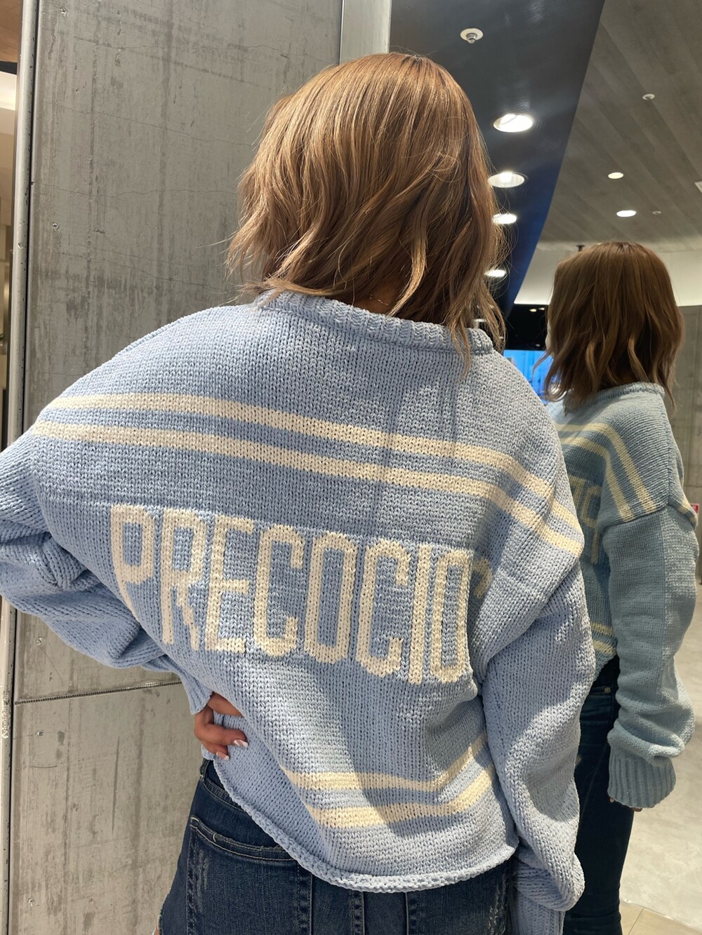 ブルー系のニット/セーター、ブルー系のデニムパンツ、ホワイト系のパンプスを着用したレディースの冬コーディネートの2枚目の写真