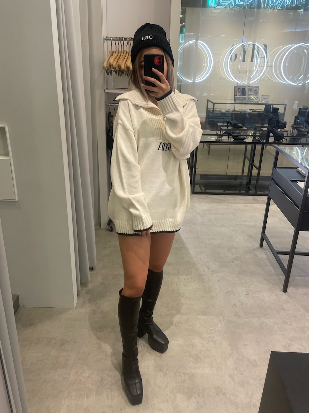 ホワイト系のニット/セーター、ブラック系のスカート、ブラック系のブーツを着用したレディースの冬コーディネートの2枚目の写真