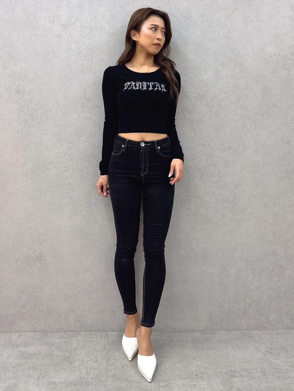 ブラック系のニット/セーター、ブラック系のデニムパンツ、ホワイト系のパンプスを着用したレディースの春コーディネートの2枚目の写真