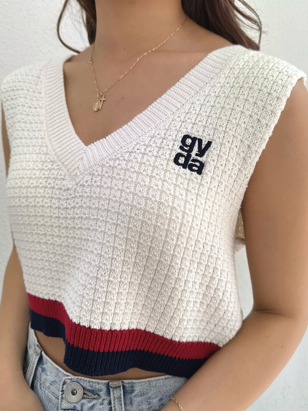 ホワイト系のニット/セーター、ブルー系のデニムパンツ、ホワイト系のパンプスを着用したレディースの春コーディネートの7枚目の写真