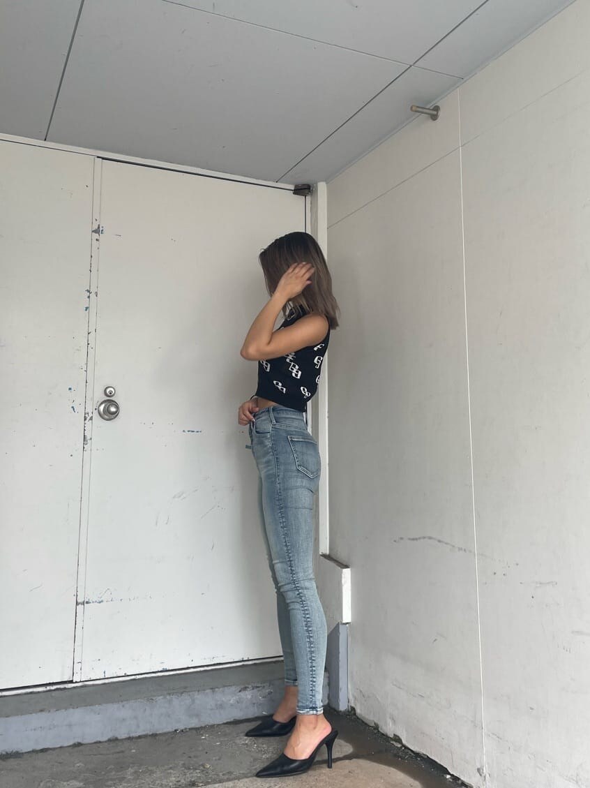 ブラック系のパンプス、ブラック系のニット/セーター、ブルー系のデニムパンツを着用したレディースの春コーディネートの3枚目の写真