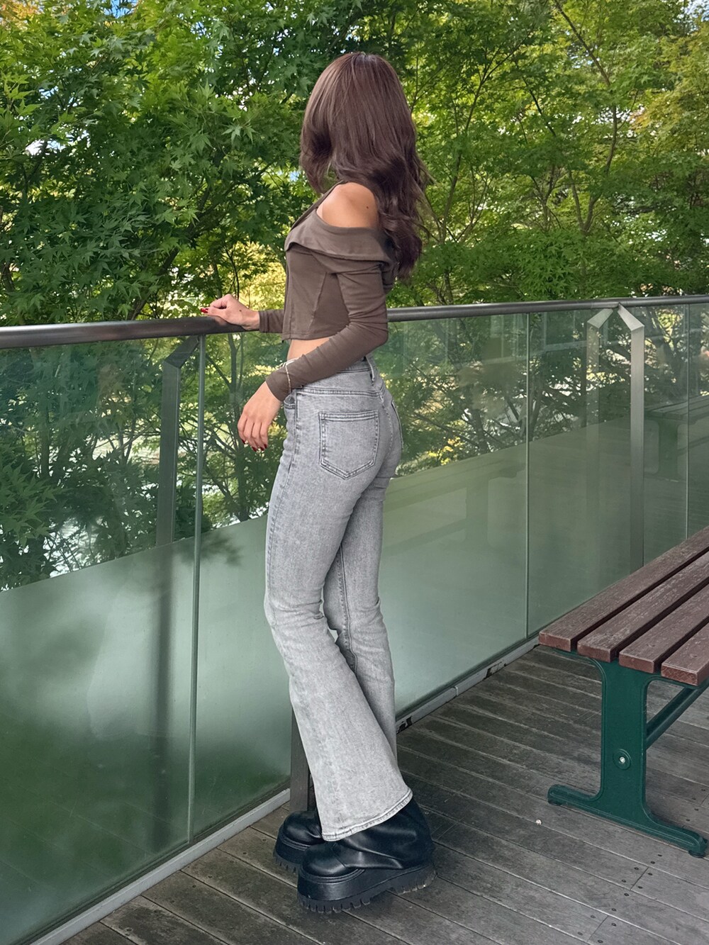 グリーン系のTシャツ/カットソー、グレー系のデニムパンツ、ブラック系のブーツを着用したレディースの秋コーディネートの2枚目の写真