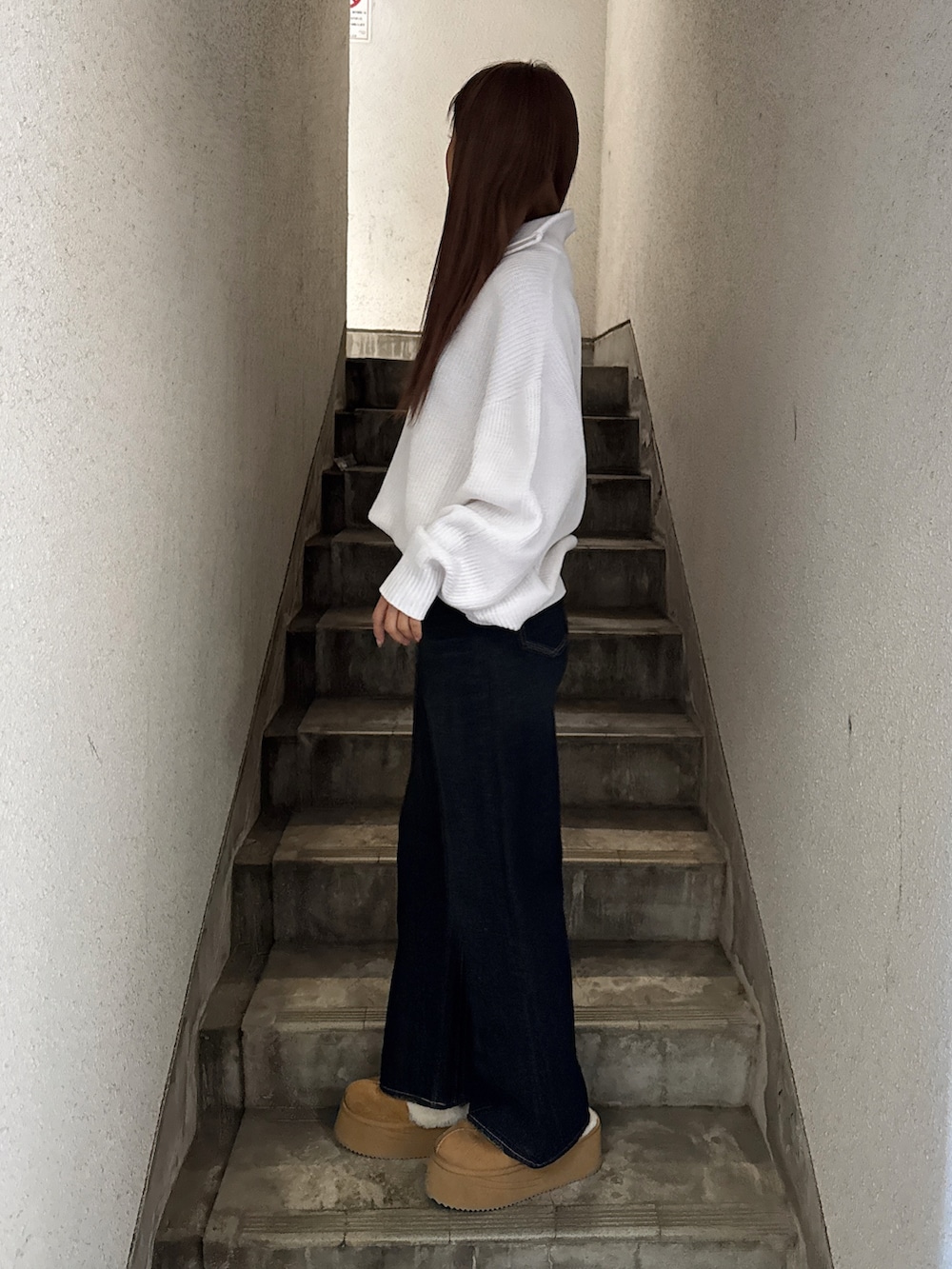 ホワイト系のニット/セーター、ブルー系のデニムパンツ、ベージュ系のスリッポンを着用したレディースの冬コーディネートの2枚目の写真