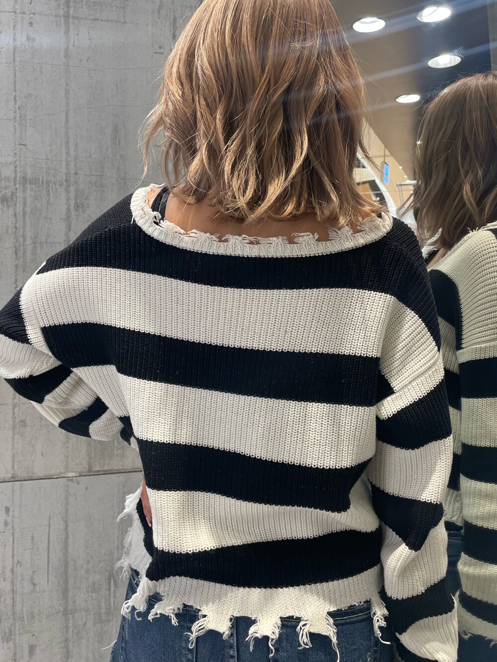 ブルー系のデニムパンツ、ホワイト系のパンプス、ブラック系のニット/セーターを着用したレディースの冬コーディネートの6枚目の写真