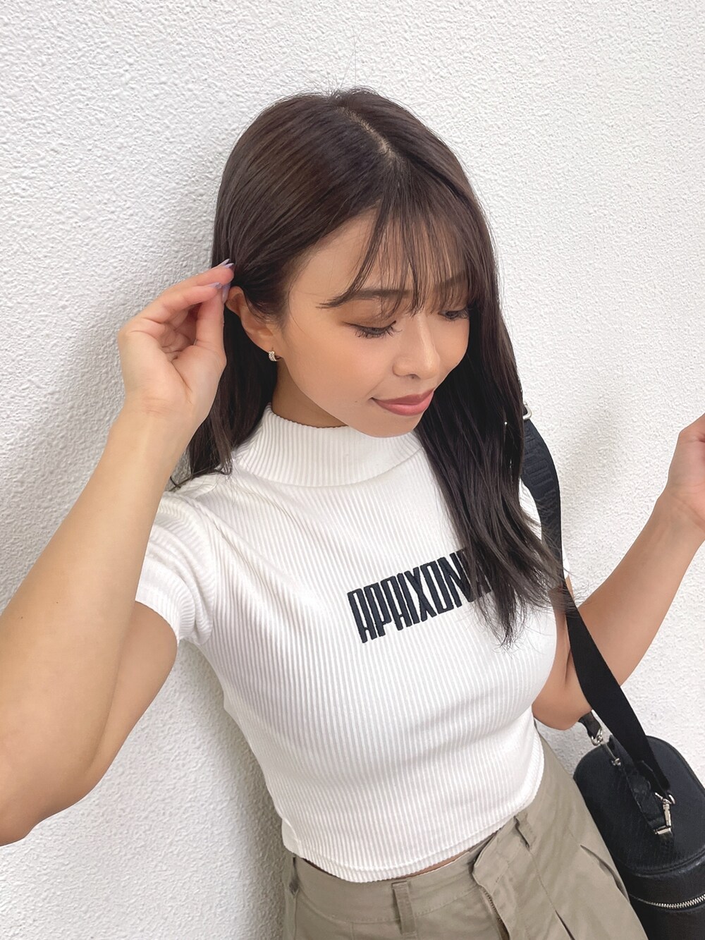 ブラック系のブーツ、ブラック系のハンドバッグ、ベージュ系のスカートを着用したレディースの春コーディネートの5枚目の写真