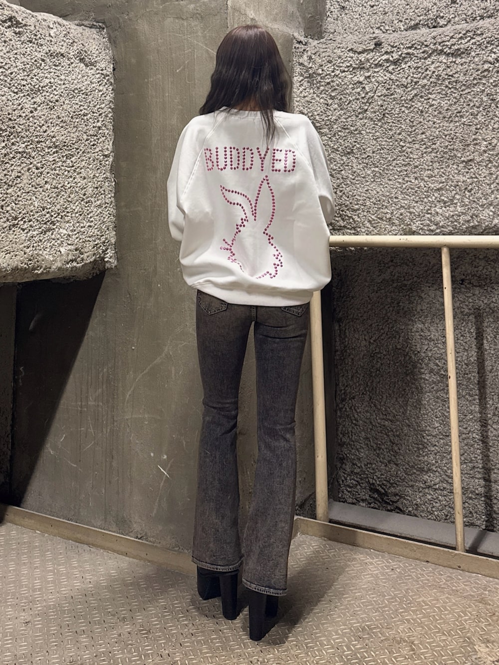 ホワイト系のスウェット、ブルー系のデニムパンツ、ブラック系のブーツを着用したレディースの冬コーディネートの4枚目の写真