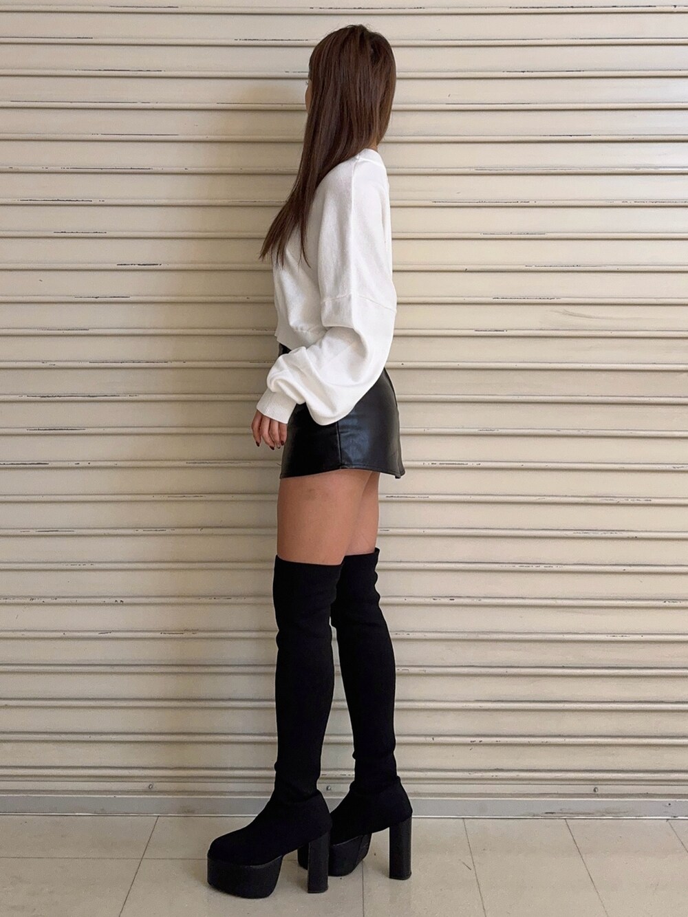 ホワイト系のニット/セーター、ブラック系のスカート、ブラック系のブーツを着用したレディースの秋コーディネートの3枚目の写真